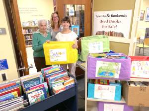Friends of the Library volunteer Leslie Faulds, member of the circulation staff and liaison to the Friends of the Library Lauren Hoffman, and AWPL Director Lisa Laico stand amid books donated by PIE students from Sanfordville Elementary School.