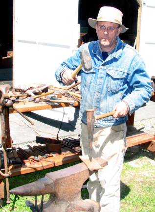 Photos by Roger Gavan Robert Schmick, director of the Historical Society of the Town of Warwick, demonstrates how holes in metal objects were made by hammering a spike on the hot metal placed over a hole in the anvil. Most of the primitive stoves and tools used in the course came from his private collection.