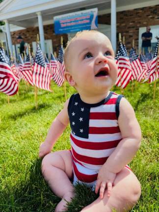 Every year at Memorial Day, the Lazear, Smith and VanderPlaat Memorial Home on Oakland Avenue in Warwick decorates its front lawn with flags in memory of veterans who have passed away. This year the company placed 2003 flags. This tradition has been continuing for many years, and has been passed down through generations. Pictured here is Michael Steven Arbuco Jr., helping to carry on the tradition. He is the grandson of Steven Arbuco, a long time employee of the memorial home.