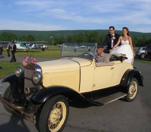 The happy couple, now Mr. and Mrs. Gruman, were given a tour of the area in a bright yellow 1930 Model A Ford convertible owned and driven by Airport Manager Dave Mac Millan. And, adding to the merriment of the occasion, that's how they arrived at the airport reception.