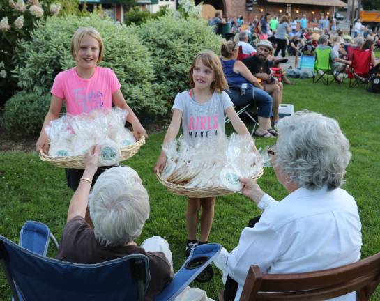 From left, Abigail Kane, 9, and her sister Anna, 7 helped distribute 400 sugar cookies featuring the Sesquicentennial logo to everyone at the concert.