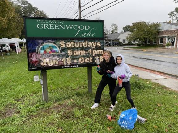 Two scouts stand in front of the Greenwood Lake sign.