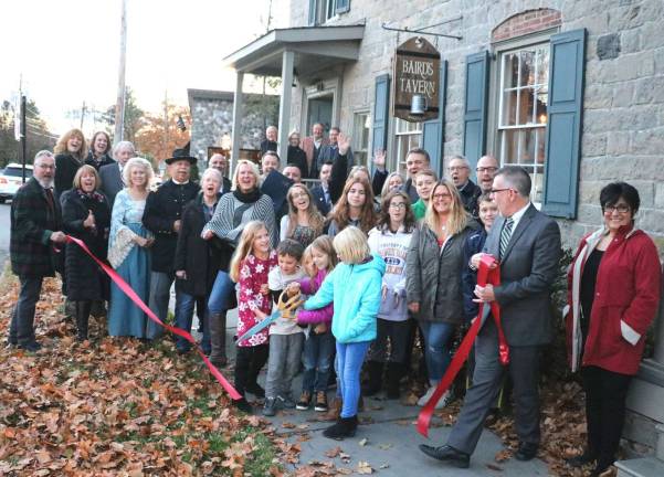 Photo by Roger GvanOn Thursday, Nov. 16, Town of Warwick Supervisor Michael Sweeton (far right), Mayor Michael Newhard (far left) and members of the Warwick Valley Chamber of Commerce joined Adam Powers (rear right), his staff, officials and members of the Warwick Historical Society and their families and friends to celebrate the official grand opening of Baird's Tavern with a ribbon-cutting.