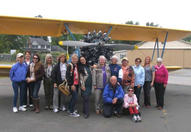 Photo by Roger Gavan Members of the North Jersey Chapter of the &quot;Ninety Nines,&quot; an International organization of women pilots, pose in front of a World War II-era PT-17 trainer, owned by Warwick Municipal Airport Manager Dave Mac Millan (center), who talked Chapter Chair Shannon Osborne into wearing a parachute for the photo.