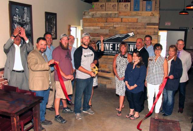 Photo by Roger Gavan On Thursday, June 16, Orange County Legislator Paul Ruszkiewicz (front left), Town of Warwick Deputy Supervisor James Gerstner(fifth from right) and members of the Warwick Valley Chamber of Commerce joined Mike Kraai (center), owner and brewmaster, and his Sales Manager, Eddie Gorter, for the official grand opening of Pine Island Brewing.