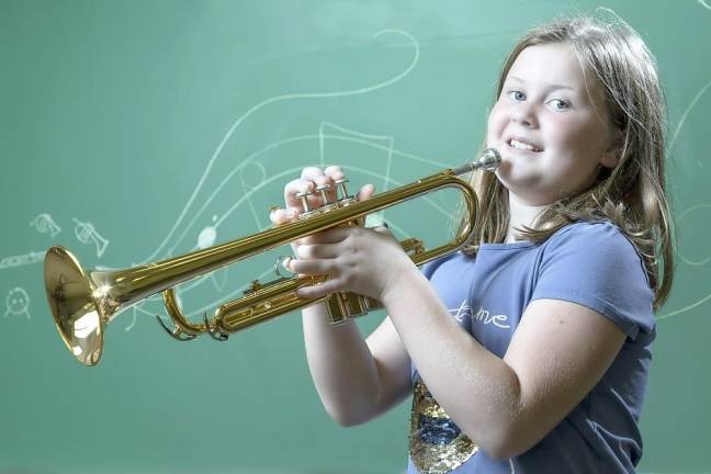 Portrait of school girl (8-9) playing trumpet during music class