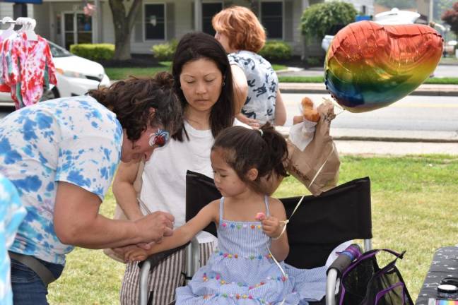 Hazel Sigman, 3, has a colorful wipe-off tattoo applied to her arm. Behind her is her mother, Sue Lee.