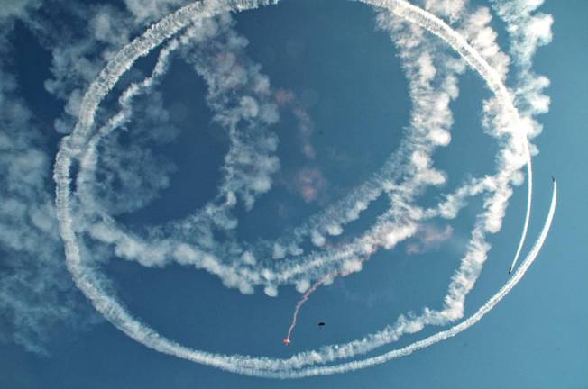 Rob Holland, one of the airshow pilots, performs “Circle the Jumpers” where he circles the skydivers with smoke as they jump.