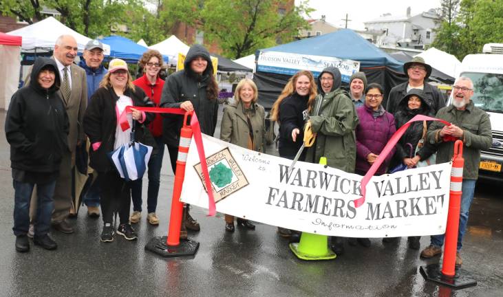 Photo by Roger Gavan On Sunday, May 12, Town of Warwick Deputy Supervisor James Gerstner (left), Mayor Michael Newhard (right)and members of the Warwick Valley Chamber of Commerce joined Cheryl Rogowski (center), chair of the Warwick Valley Farmers Market, committee members and vendors for a ribbon-cutting ceremony to officially kick off the market season.