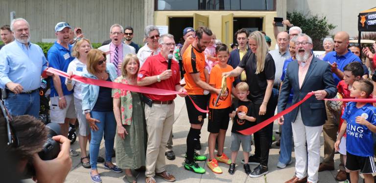 On Saturday, June 1, local officials including Town of Warwick Supevisor Michael Sweeton (holding microphone) and Mayor Michael Newhard (far right) along with members of the Warwick Valley Chamber of Commerce joined owners Christian and Raluca Fuchs (center), their family, staff and associates to celebrate the official grand opening of the Hudson Sports Complex.